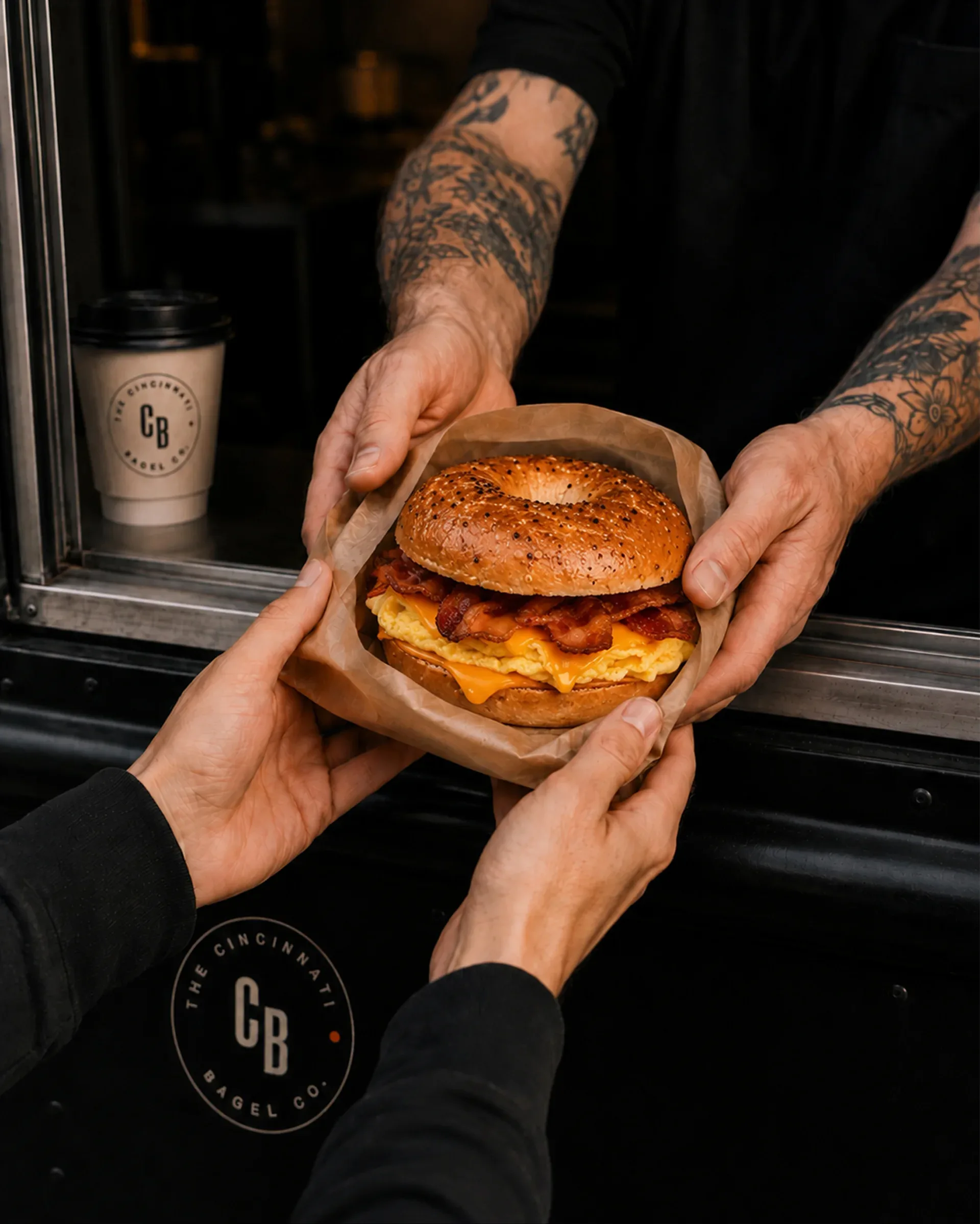 The Cincinnati Bagel Co. — A Cincinnati Bagel Co. breakfast sandwich handoff at the shop window
