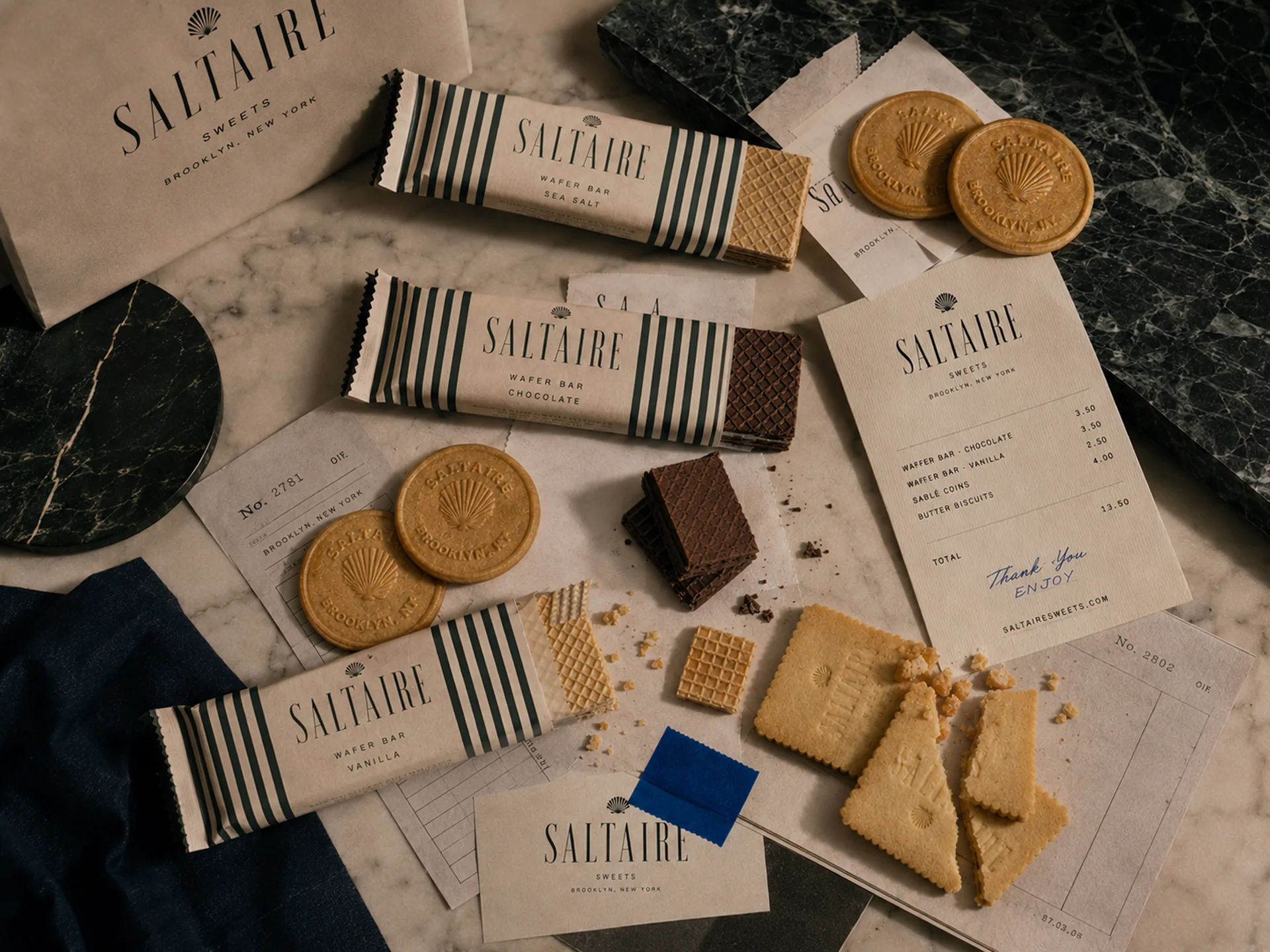 SALTAIRE wafers, chocolate bars, stamped cookies, receipts, and handwritten notes spread across marble