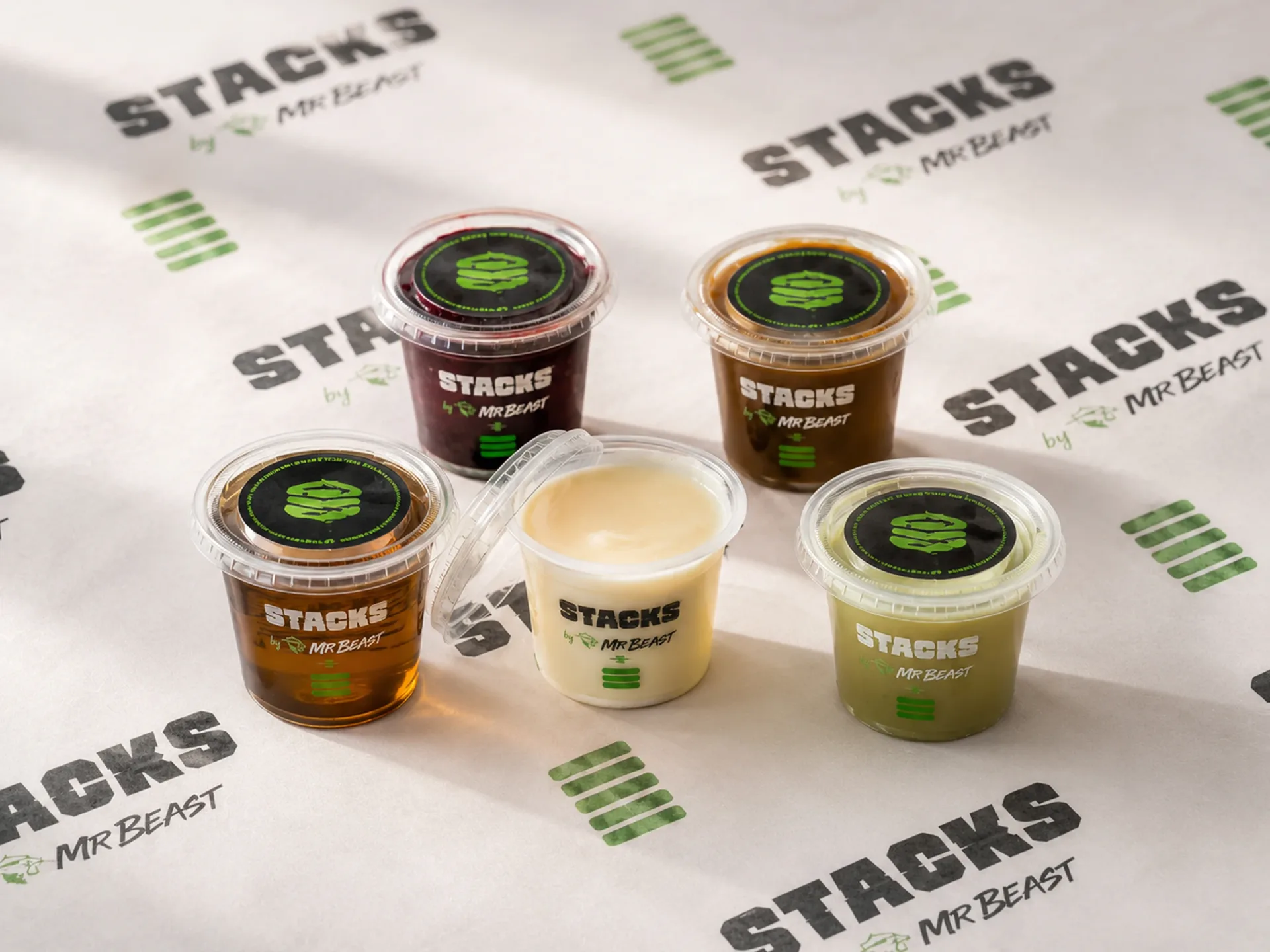 Stacks branded sauce and topping cups arranged on repeated Stacks wrap paper